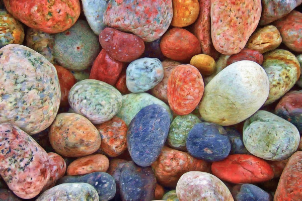 Close-up of smooth, multicoloured stones of different shapes and sizes arranged closely together, symbolizing diversity and unity.